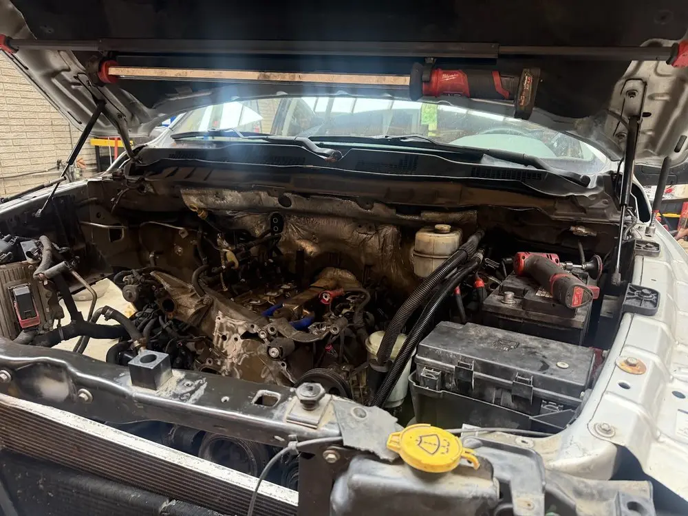 Pickup truck engine bay under shop lights during diesel service