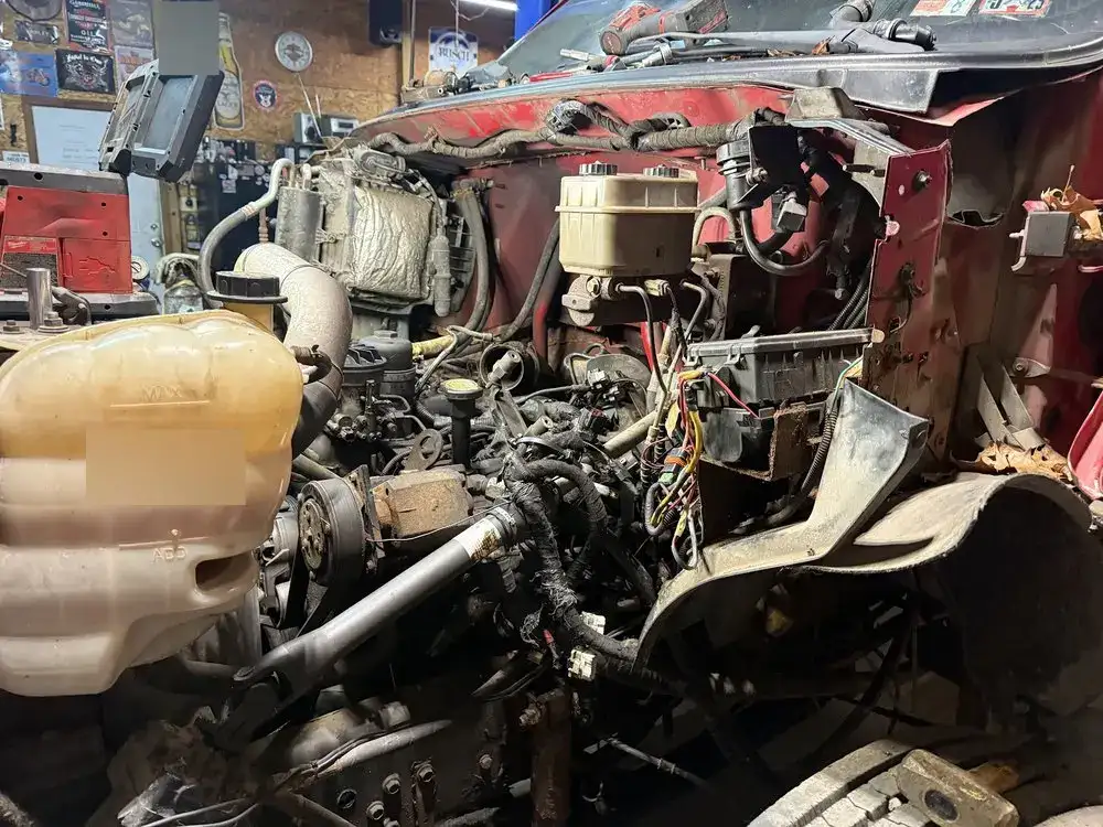 Truck engine compartment opened up with wiring, coolant tank and brake parts exposed for repair