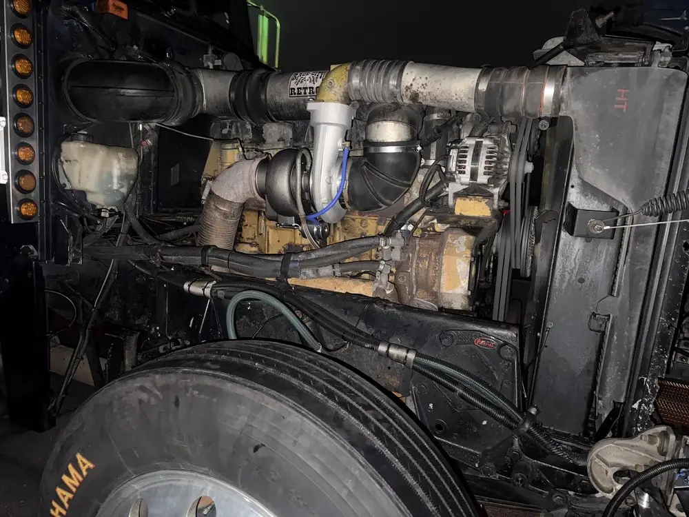 Semi truck engine and turbo seen from the side with the hood tilted forward